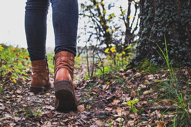 istock Female legs shod in Hiking boots on the forest background 613529208