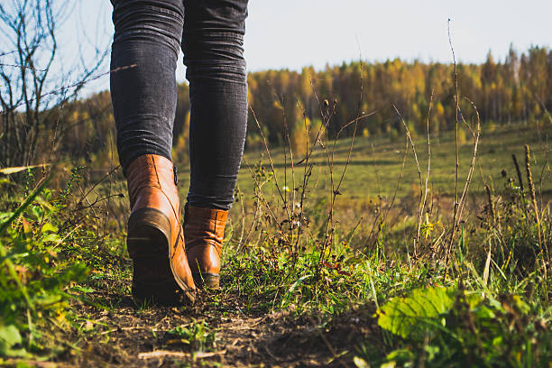 istock Female legs shod in Hiking boots on the forest background 613529690