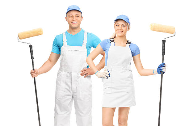 istock Male and female decorators holding paint rollers 613530202