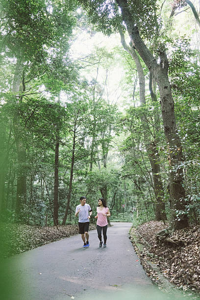 istock Cheerful Japanese couple running outdoors in a park 613532528