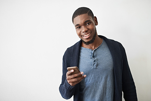 Studio portrait of a young man using a cellphone against a gray background