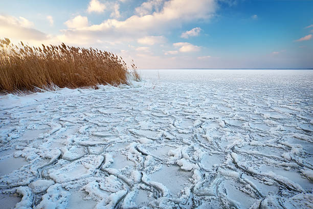 istock Winter landscape with frozen lake and sunset sky. Composition of 613541124