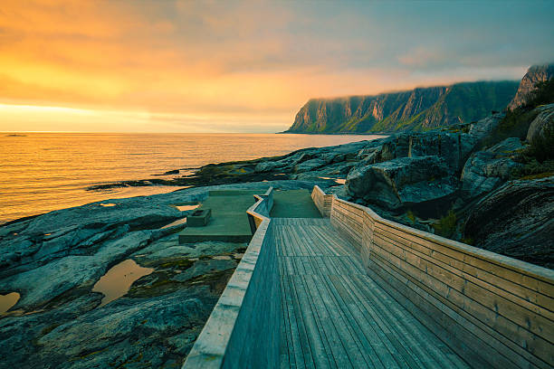 Wooden pathway on the rocky beach Senja island at orange sunset. Wooden pathway on the rocky beach senja island photos stock pictures, royalty-free photos & images