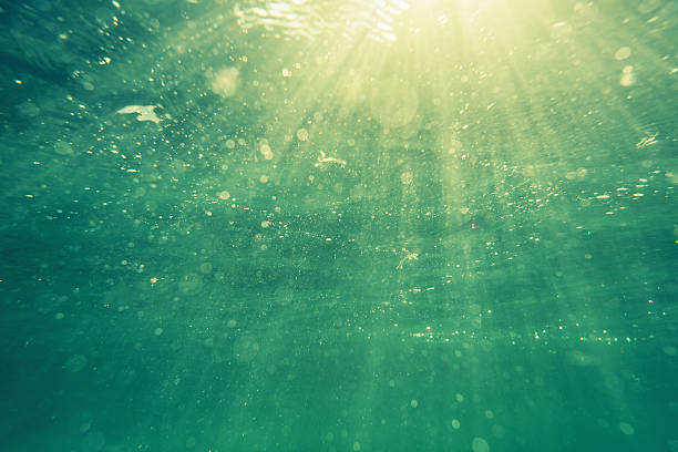 Underwater shot with sunrays and bubbles in deep tropical sea