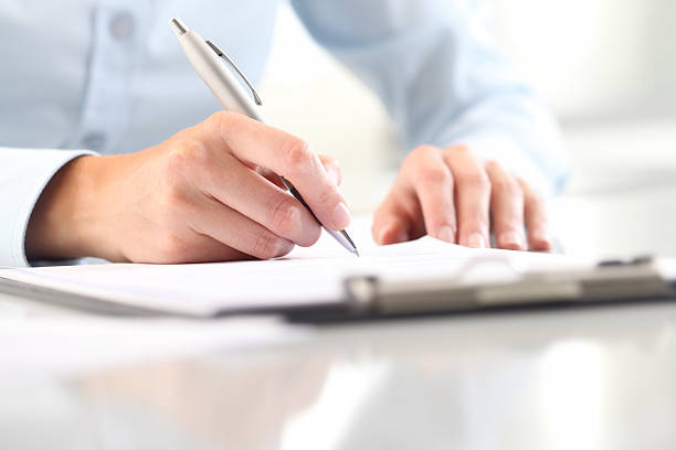 istock Woman's hands writing on sheet in clipboard with a pen 613542110