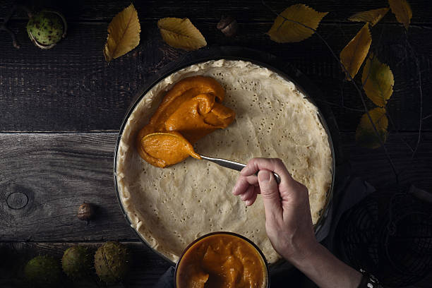 istock Putting  pumpkin puree on the dough for pumpkin pie horizontal 613542162