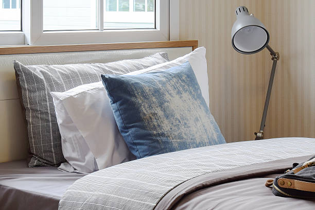 istock cozy bedroom with pillows and reading lamp on bedside table 613542964