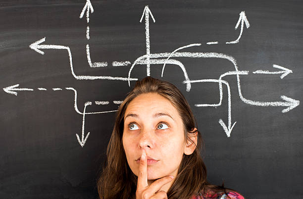 Arrow sketch on blackboard and pretty young woman smiling to camera. Concept of decision making