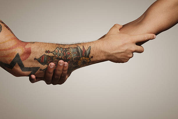 Close up shot of a forearm handshake Close up of a forearm Roman, Civil war handshake of two young men, one with tattoos, on white background forearm tattoos men stock pictures, royalty-free photos & images