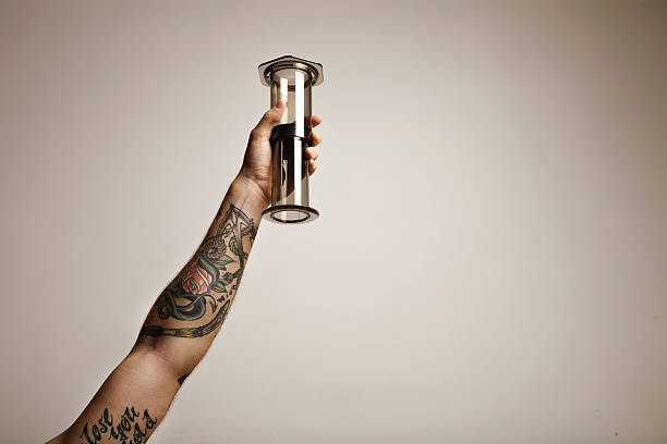 Hand with tattoos holding aeropress