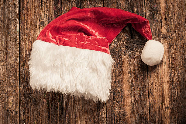 istock Santa red hat on wooden background 613549372