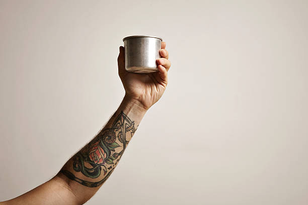 istock Tattooed hand with metal travel cup 613550290