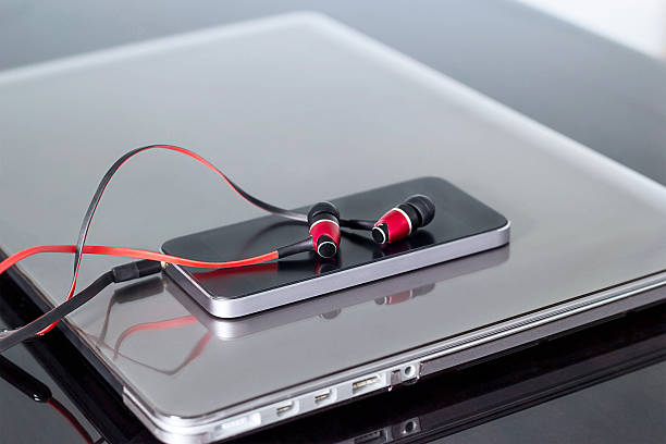 istock Red earphones and mobile phone on laptop background 613550960