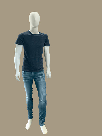 Full length male mannequin dressed in t-shirt and jeans, isolated on brown background. No brand names or copyright objects.