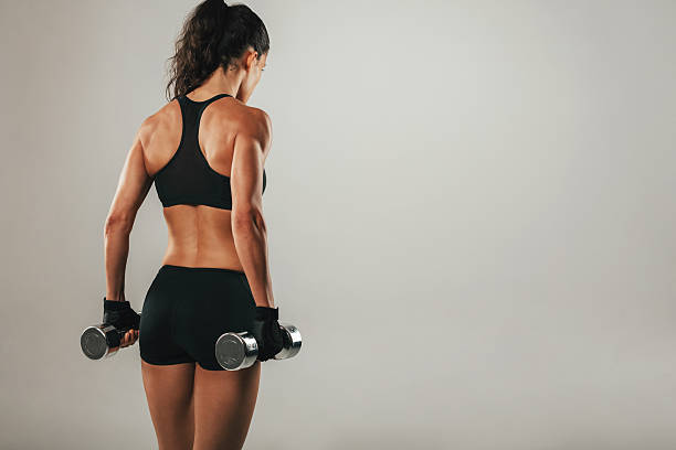istock Back of athletic woman holding weights 613553074