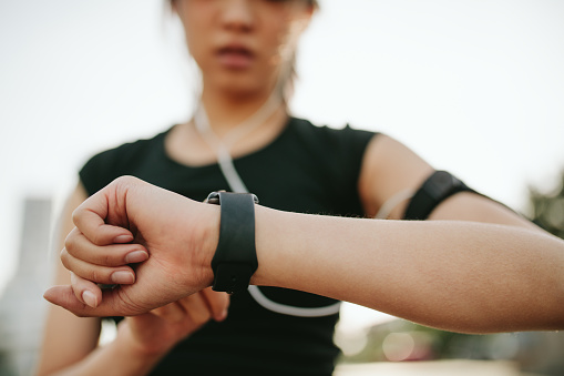 Close up shot of young sportswoman using smartwatch to track her workout performance. Fitness female monitoring her progress on smartwatch.