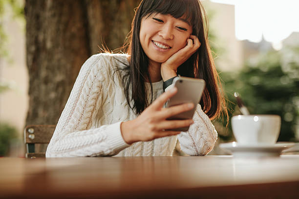 Happy young woman using her cellphone at cafe