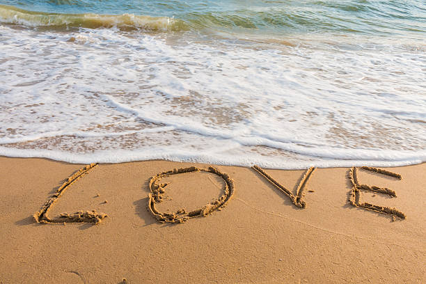istock alphabet letters love handwritten in sand on beach 613556096