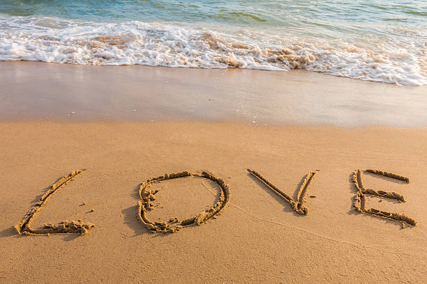 istock alphabet letters love handwritten in sand on beach 613556254