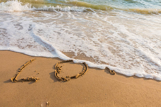 istock alphabet letters love handwritten in sand on beach 613556310