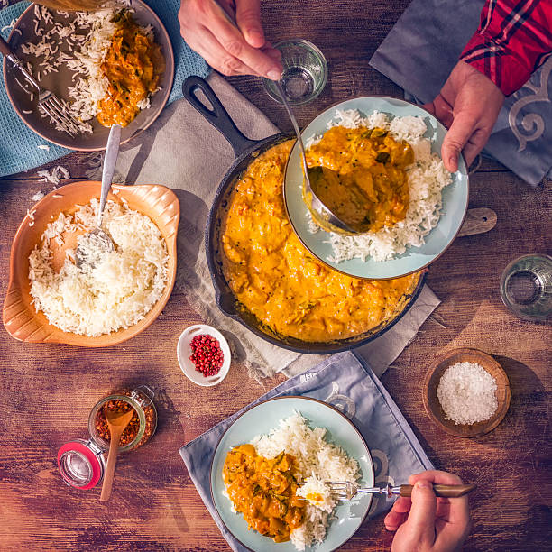 Eating Delicous Homemade Chicken Curry Dish with Rice Young family eating delicious homemade chicken curry dish with basmati rice. indian dinner stock pictures, royalty-free photos & images