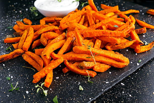 papas fritas de batata de naranja al horno caseras saludables con crema fresca - sweet potato french fries yam baked fotografías e imágenes de stock