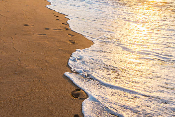 istock Footprints in the Sand reflective  at sunset time 613557912