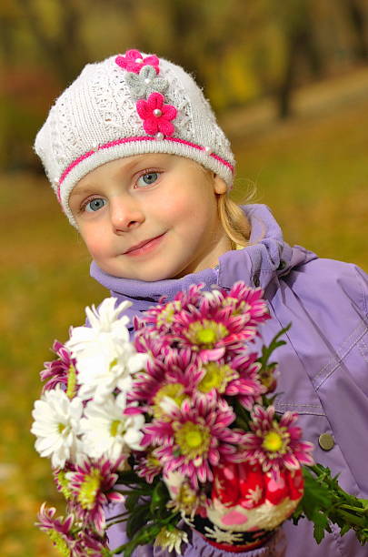 istock child standing with flowers in the park 613559774