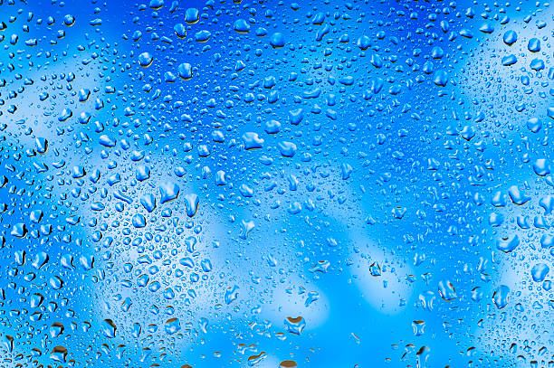 istock Water drops on glass with sky and clouds background 613561042