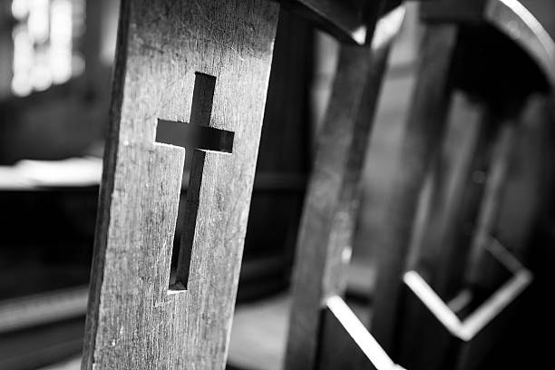 Pew. Black & white image of a crucifix cut into a church pew. anglican stock pictures, royalty-free photos & images