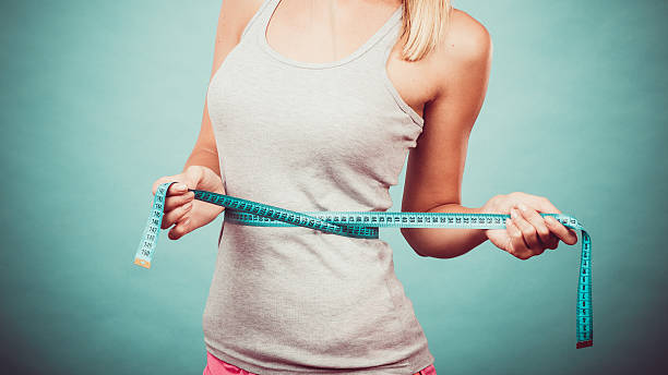 chica medir su waistline gimnasio - loose weight fotografías e imágenes de stock