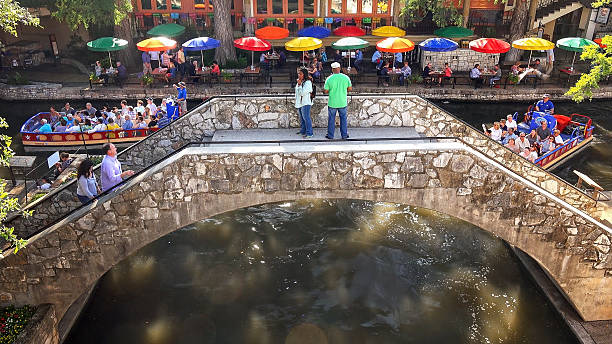 les touristes traversent le pont à san antonio river walk, texas - san antonio riverwalk downtown district river photos et images de collection