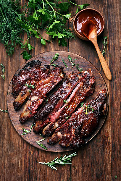 Grilled sliced barbecue pork ribs Grilled sliced barbecue pork ribs, green herbs and tomato sauce, top view steak vertical beef meat stock pictures, royalty-free photos & images