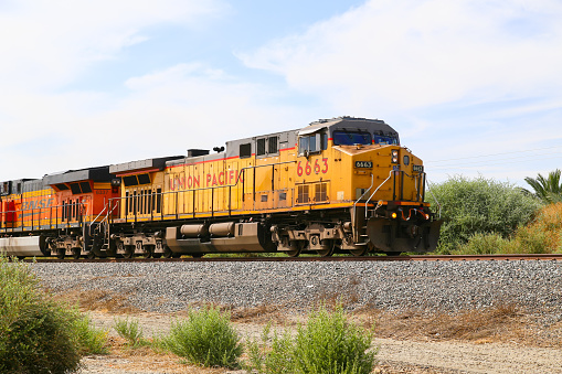 Mecca, California, United States - May 26, 2015: Freight train with both Union Pacific and BNSF engines on track next to California State Route 111.