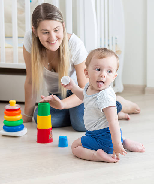 istock Smiling mother assembling toy pyramid with her baby boy 613655238