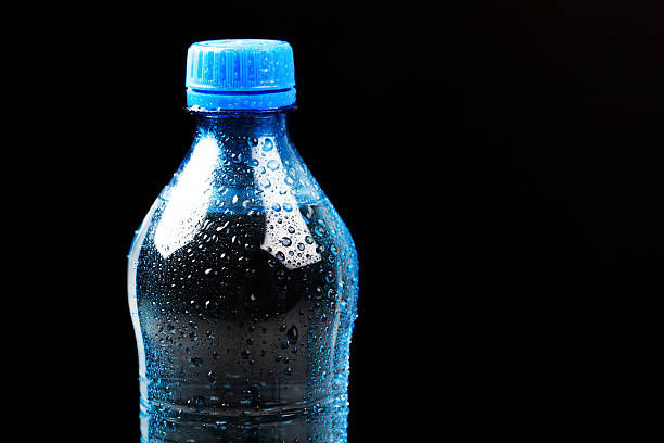 istock Blue plastic bottle of water isolated on black 613655552