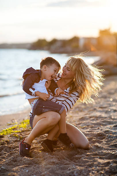 istock Beautiful woman with a child on the beach 613656464