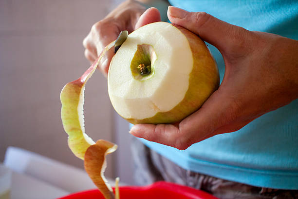 frau peeling äpfel in der küche - schälen essen zubereiten stock-fotos und bilder