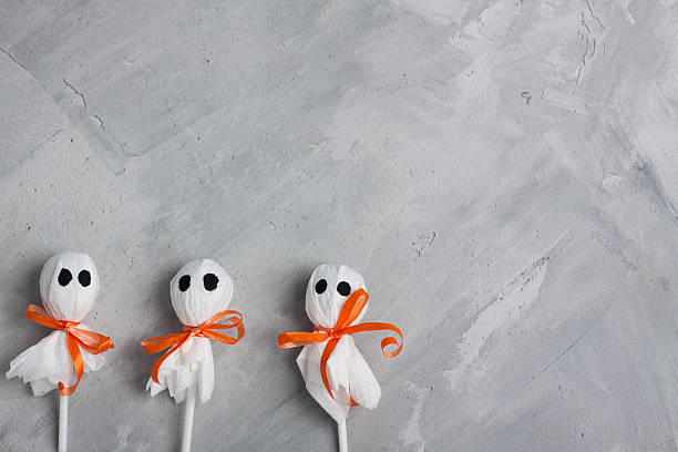 istock Three halloween lollipop ghosts on gray concrete background 613657580