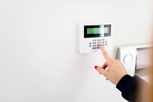 jeune femme entrant le code de sécurité sur le clavier - security system security burglar alarm home interior photos et images de collection