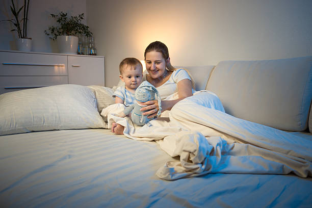 istock Mother playing with her baby at night with doll 613658718