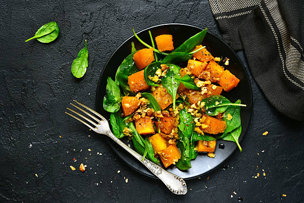 istock Roasted pumpkin salad with spinach and walnut .Top view. 613663896