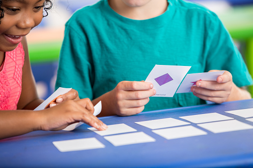 Male and female kindergarten students play with flash cards in class.