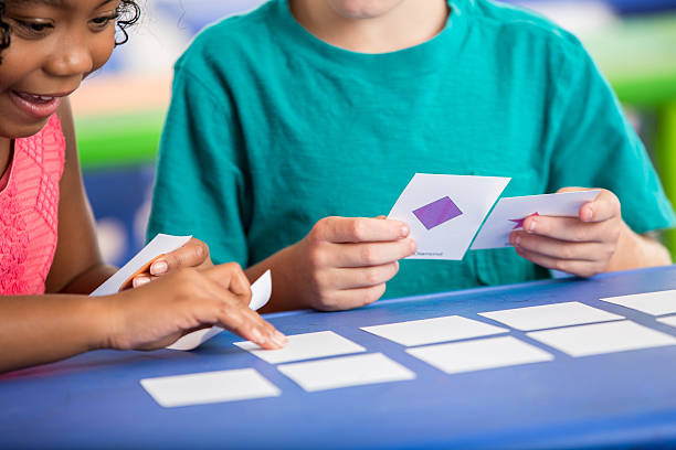 Diverse kindergarten friends use flash cards Male and female kindergarten students play with flash cards in class. discover card stock pictures, royalty-free photos & images