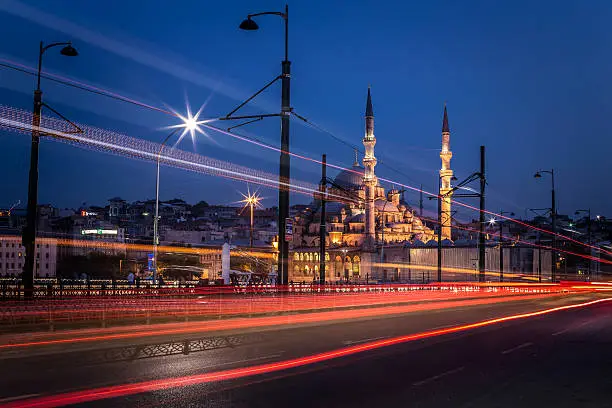 A long exposure image of Yeni Cami mosque in Istanbul, Turkey during the blue hour with traffic light trails. Photographed from the Galata Bridge. Shot on Canon EOS full frame system with L lens on a tripod.