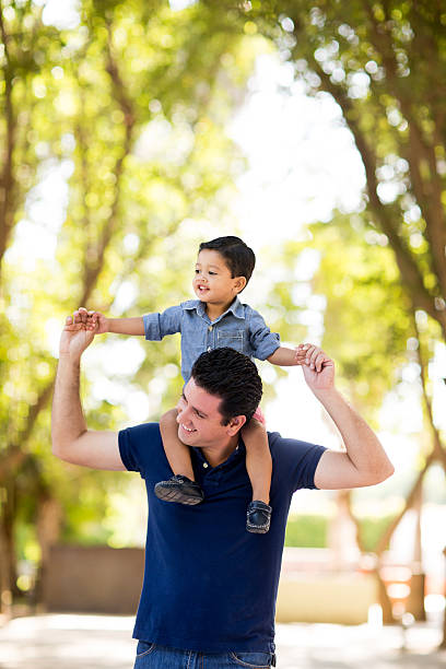 istock Young latin father carrying son on shoulders 613666046