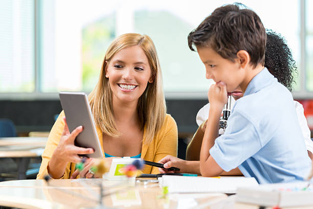 istock STEM school teacher uses digital tablet to help student 613666090