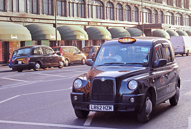 Black cab Knighstbridge London, United Kingdom - February 9, 2015: Traditional taxi service black cab car on street with other cars in background near Harrods department store in London harrods photos stock pictures, royalty-free photos & images