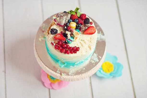istock Smash cake with cream and berries on a white wooden 613669282