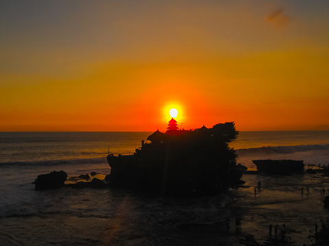 Tanah Lot and sea waves in golden sunset at Bali